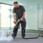 a male cleaning contractor steam cleans an office carpet in a empty office in between tenants.